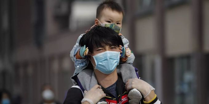 Ein Mann mit einem Kleinkind auf den Schultern in Beijing. Virus Outbreak China