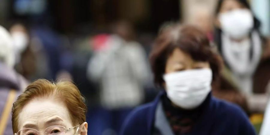 Fussgänger in Tokio tragen Schutzmasken. Mit der gerade laufenden Reisewelle zum chinesischen Neujahrsfest wächst die Gefahr einer Übertragung des Virus. Foto: Eugene Hoshiko/AP/dpa