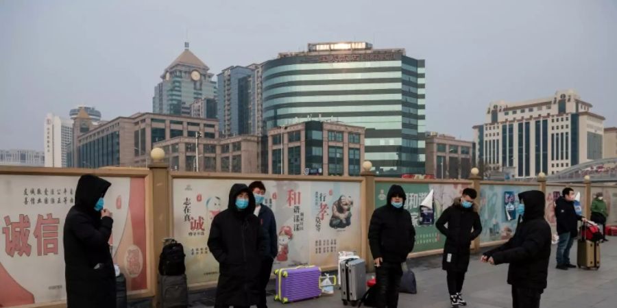 Menschen mit Atemschutzmasken am Bahnhof von Peking