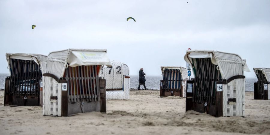 Spaziergänger laufen bei Regen über den Strand von Norddeich. Kurzentschlossene, die über die Festtage noch verreisen wollen, haben in Niedersachsen Chancen, noch eine Unterkunft zu finden.