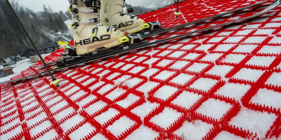 Ein Mann steht mit seinen Skiern auf einer Skipiste, die mit speziellen Kunststoff-Matten präpariert wurde. Die Matten können das ganze Jahr über zum Skifahren verwendet werden.