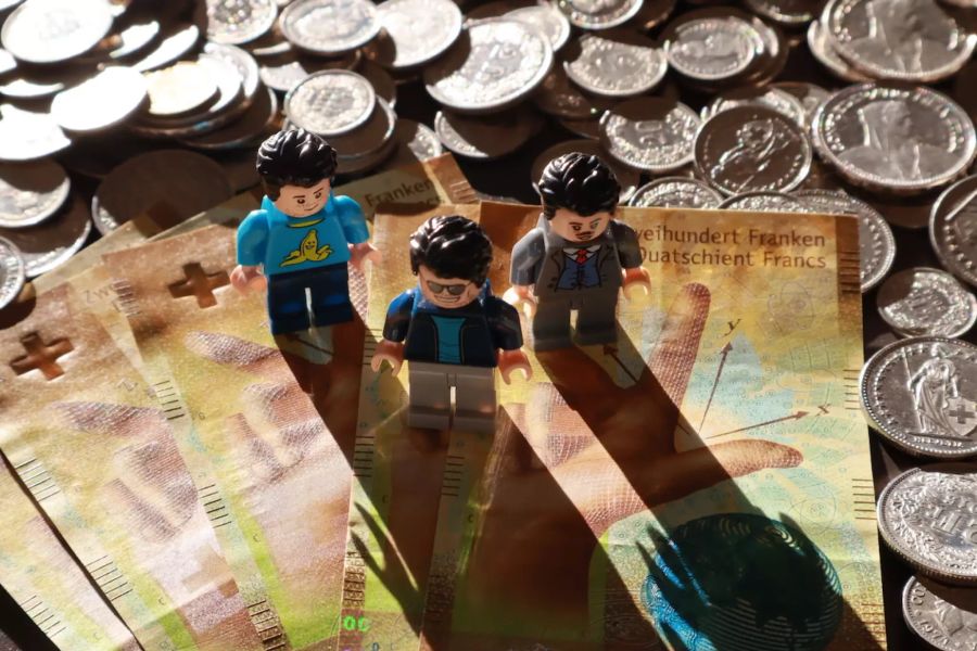 Drei Legomännchen stehen auf Banknoten