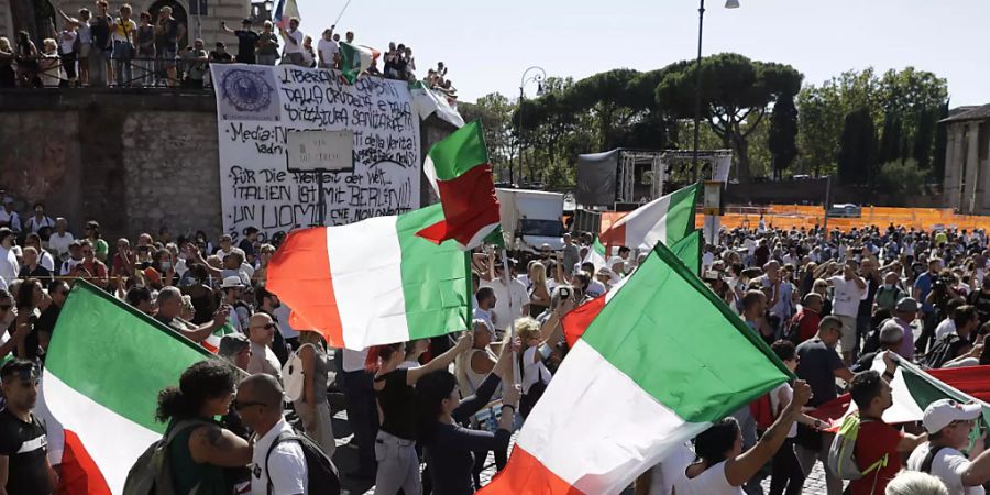 Teilnehmer einer Demonstration gegen die staatliche Corona-Politik schwenken italienische Nationalflaggen. Foto: Gregorio Borgia/AP/dpa