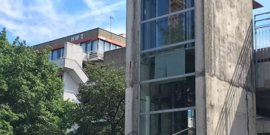 Rettunskräfte und Polizisten stehen auf dem Gelände der Bremer Universität zusammen. In Bremen ist ein Mann nach einer Gewalttat auf das Dach eines Universitätsgebäudes geflohen. Foto: Christina Kuhaupt/dpa