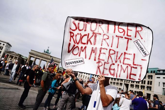 Ein Teilnehmer mit dem Plakat «Sofortiger Rücktritt vom Merkel-Regime!» steht vor einer Demonstration gegen die Corona-Massnahmen am Brandcenburger Tor. Protest gegen Corona-Massnahmen Berlin