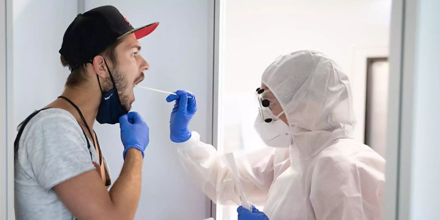 ARCHIV - Eine Mitarbeiterin testet bei einem Medientermin im neuen, kommerziellen Covid-19-Testzentrum am Flughafen Hamburg einen Urlauber nach seiner Rückkehr. Foto: Christian Charisius/dpa - ACHTUNG: Nur zur redaktionellen Verwendung im Zusammenhang mit einer Berichterstattung über das neue Covid-19-Testzentrum in Hamburg und nur mit vollständiger Nennung des vorstehenden Credits