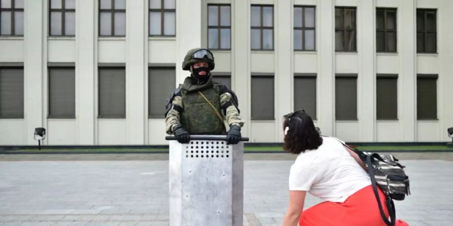 Eine Frau legt Blumen vor einem Wachposten nieder