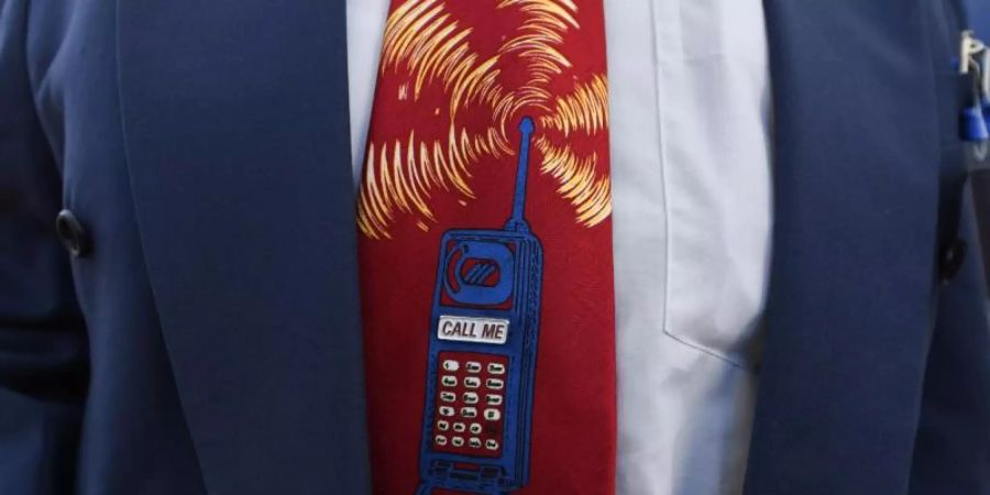 Ein Bieter trägt beim Start der Auktion von 5G-Mobilfunkfrequenzblöcken am Mainzer Technik-Standort der Bundesnetzagentur eine Krawatte mit einem Mobiltelefon. Foto: Arne Dedert