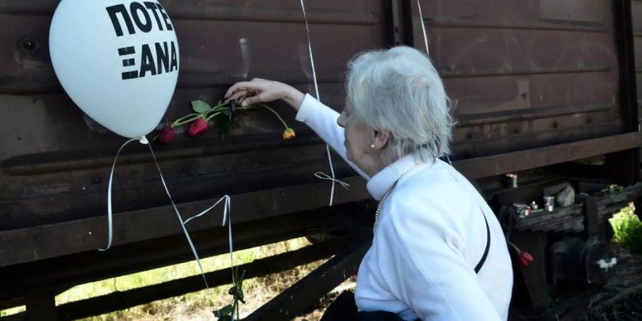 Eine Frau steckt Blumen zum Gedenken an einen Waggon