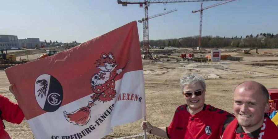 Fans stehen bei der Grundsteinlegung vor der Baustelle für das neue Stadion des SC Freiburg. Foto: Patrick Seeger/dpa