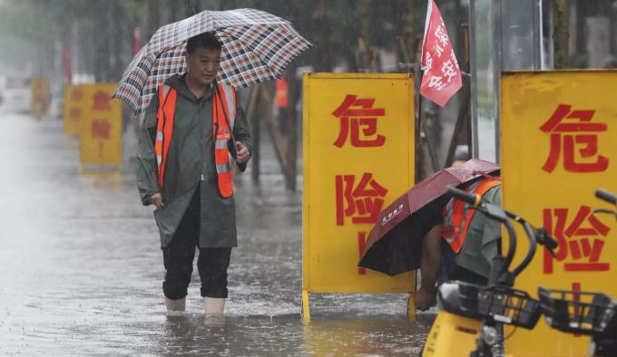 Ein Mann watet durch die Wassermassen nach Einsetzen des Starkregens in Zhengzhou. China Flooding