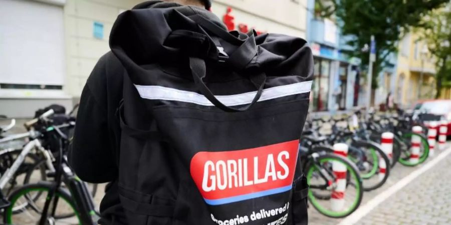 Ein Beschäftigter des Lieferdienstes Gorillas trägt einen Rucksack und steht vor den Fahrrädern. Foto: Annette Riedl/dpa