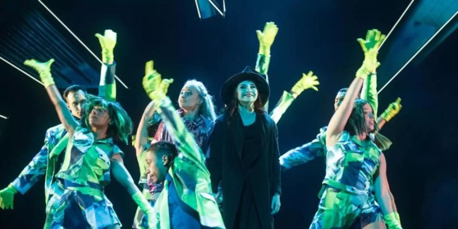 Die Sängerinnen Vajen van den Bosch (M, l.) als Elphaba und Jeannine Michele Wacker als Glinda singen und tanzen mit «Wicked»-Ensemblemitgliedern. Foto: Markus Scholz/dpa