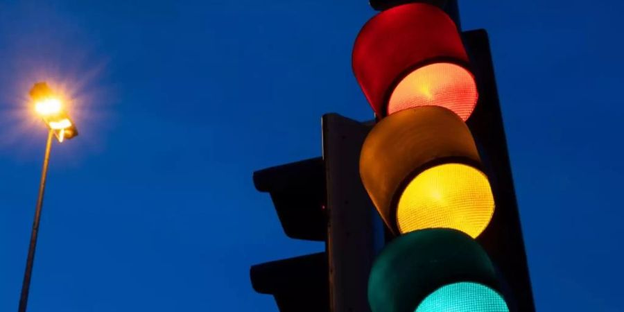 Eine Ampel zeigt am frühen Morgen die Farben rot, gelb und grün. Foto: Marijan Murat/dpa