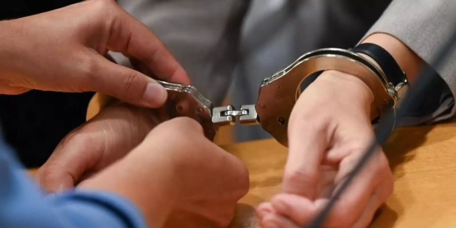 Eine Justizbeamtin nimmt der Angeklagten im Gerichtssaal des Landgerichts Hanau die Handschellen ab. Foto: Arne Dedert/dpa