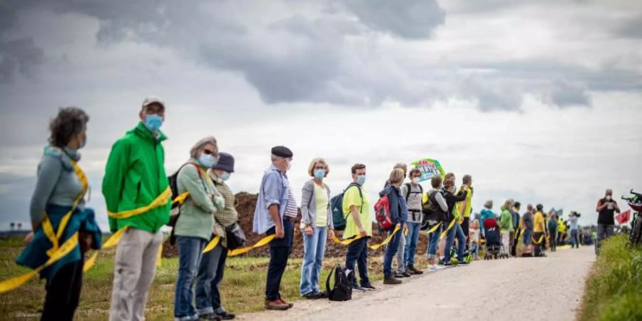 Umwelt- und Klimaschützer sowie Bewohner der angrenzenden Dörfer bilden am Rande des Braunkohletagebaus Garzweiler eine Menschenkette. Foto: Malte Krudewig/dpa
