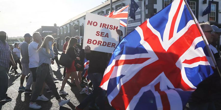 ARCHIV - Demonstranten halten britische Fahnen und ein Schild mit der Aufschrift «No Irish Sea Border» («Keine irische See-Grenze») bei einem Protest protestantischer Loyalisten gegen das sogenannte Nordirland-Protokoll. Foto: Brian Lawless/PA Wire/dpa