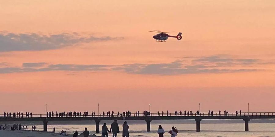 Ein Rettungshubschrauber fliegt über die Seebrücke im Ostseebad. Foto: Tilo Wallrodt/dpa