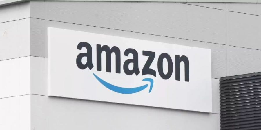 Eine Tafel mit dem Logo des Onlineversandhändlers Amazon ist an der Fassade eines Amazon-Warenlagers angebracht. Foto: Niall Carson/PA Wire/dpa