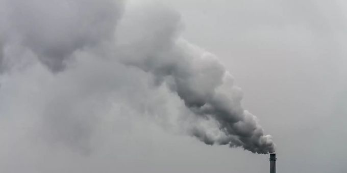 Qualm steigt aus dem Schornstein einer Fabrik. Klimaschutz
