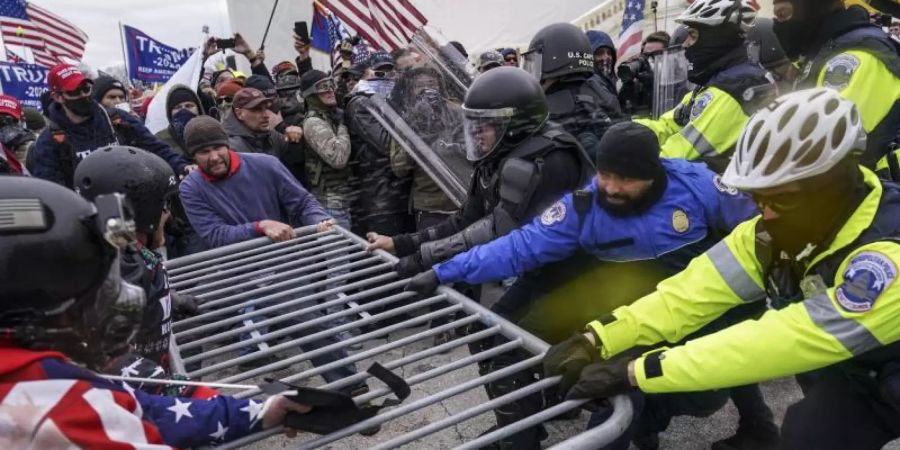 Trump-Anhänger versuchen, vor dem Kapitol durch eine Polizeiabsperrung zu brechen. Foto: John Minchillo/AP/dpa