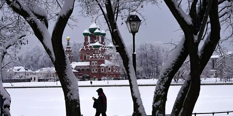 Ein Fussgänger geht durch den Schnee am zugefrorenen Ostankinsky-Teich an der Dreifaltigkeitskirche in Moskau vorbei. In der russichen Hauptstadt ist es durch starken Schneefall zu Flugausfällen und langen Staus auf den Strassen gekommen. Foto: Alexander Zemlianichenko/AP/dpa