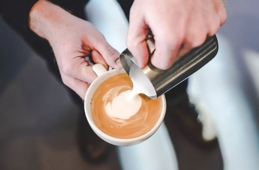 Milch in Kaffee giessen, Ansicht von oben