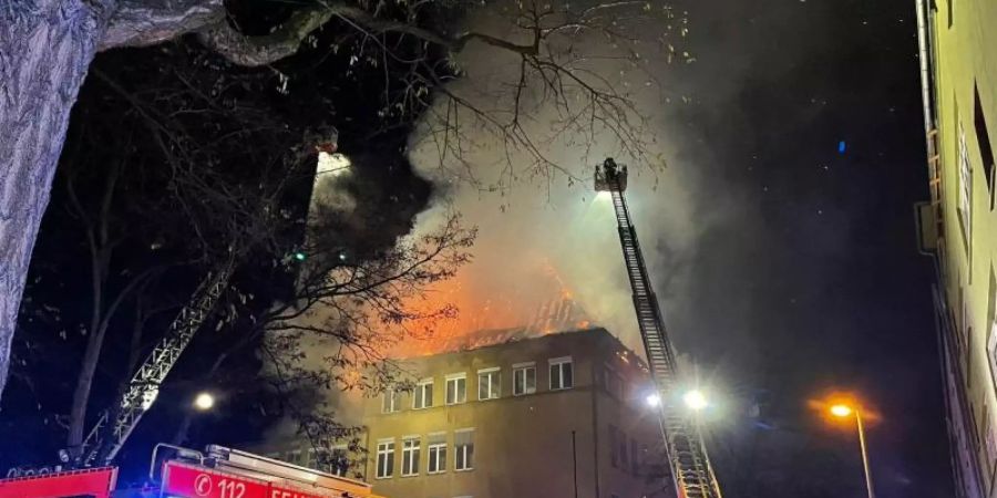 Einsatzkräfte der Feuerwehr löschen das brennende Schulgebäude. Foto: Steil-TV/dpa
