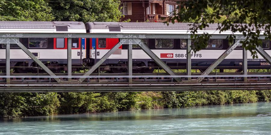 Eisenbahnbrücke über die Aare mit Zug der SBB beim Bahnhof Interlaken Ost.