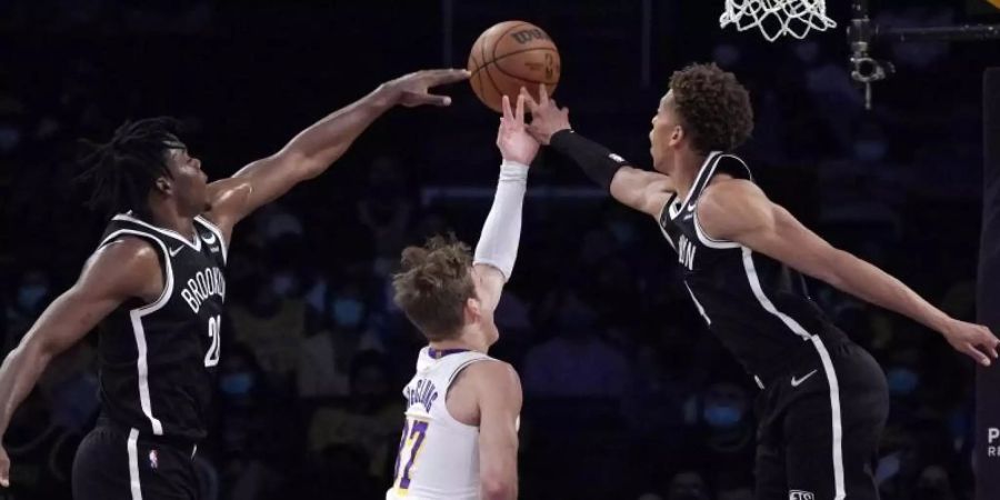 Day'Ron Sharpe (l) und Kessler Edwards (r) von den Brooklyn Nets verteidigen am Korb gegen Los Angeles Lakers-Guard Mac McClung. Foto: Mark J. Terrill/AP/dpa