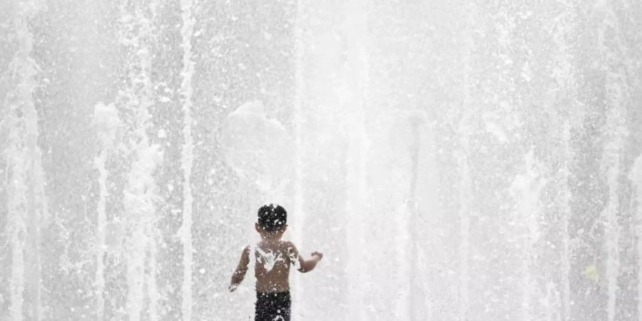 Einen Riesenspass hat ein kleiner Junge bei sommerlichen Temperaturen im Fontänenbrunnen des Walther-von-Cronberg-Platzes in Frankfurt am Main. Foto: Arne Dedert