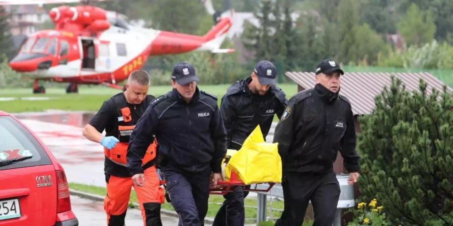 Polizisten tragen in Zakopane einen verletzten Touristen zu einem Krankenwagen. Foto: Grzegorz Momot/PAP