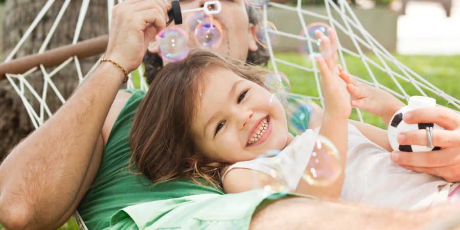 Vater und Kind liegen in Hängematte