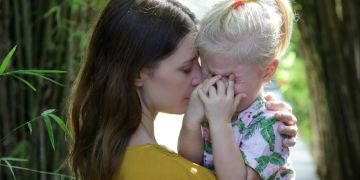 Mutter mit weinender Tochter auf dem Arm