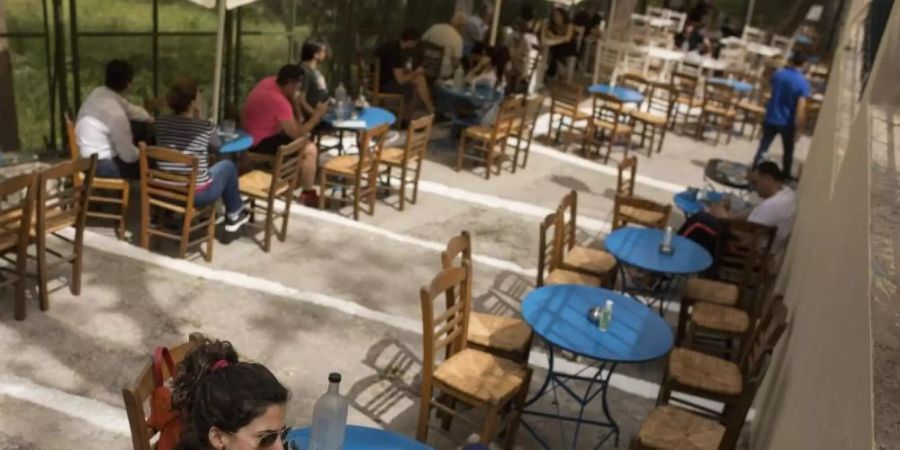 Gäste sitzen in einem Café im Stadtteil Monastiraki im Zentrum Athens. Foto: Socrates Baltagiannis/dpa