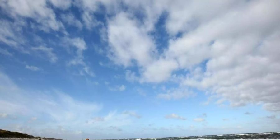 Bei windigem Wetter sind Spaziergänger am Strand von Westerland auf Sylt unterwegs. Foto: Bodo Marks/dpa