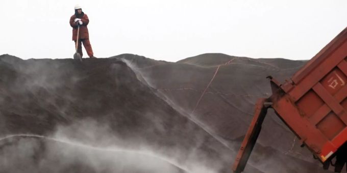 Ein Arbeiter betrachtet Lastwagen, die aus Australien importiertes Eisenerzpulver transportieren. (Archivbild) anglo american