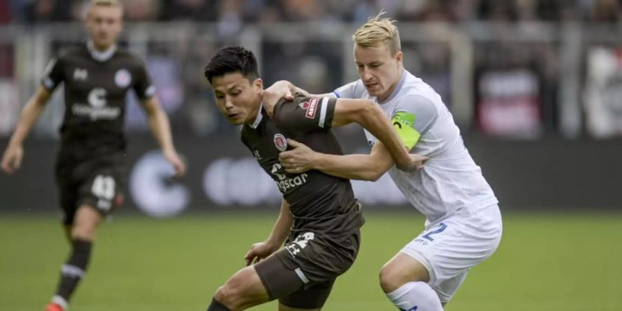 Ryo Miyaichi (l) im Zweikampf mit Fabian Holland aus Darmstadt. Foto: Axel Heimken/dpa