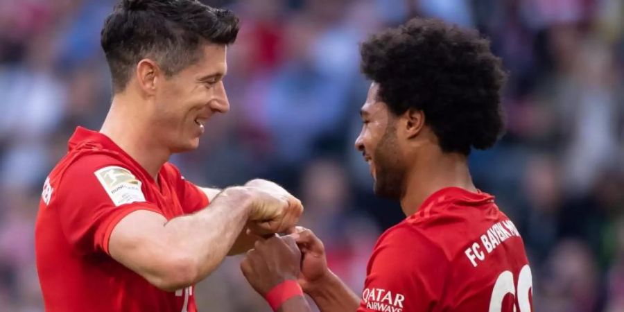 Serge Gnabry (r) gratuliert seinem Bayern-Kollegen Robert Lewandowski zum Torrekord. Foto: Sven Hoppe/dpa