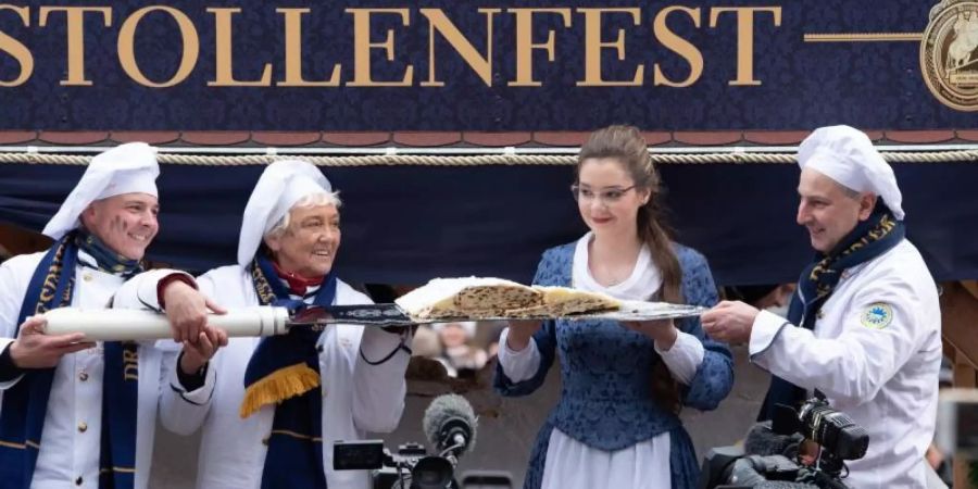 Das Dresdner Stollenmädchen und die Bäcker der Schutzgemeinschaft Dresdner Stollen präsentieren das erste Stück vom Riesenstollen. Foto: Sebastian Kahnert/dpa-Zentralbild/dpa