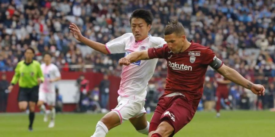 Lukas Podolski (r) im Duell um den Ball mit einem Gegenspieler. Foto: -/kyodo/dpa