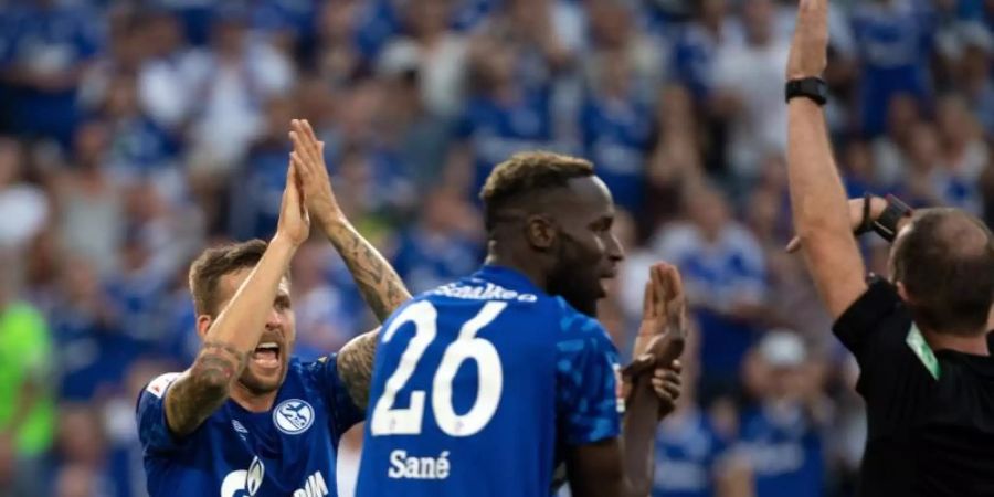 Die Schalke-Profis Salif Sane (M) und Guido Burgstaller (l) beschweren sich beim Bayern-Spiel im August bei Schiedsrichter Marco Fritz. Foto: Federico Gambarini/dpa