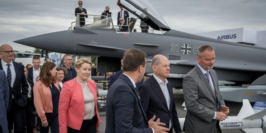 Bundeskanzler Olaf Scholz (SPD,2.v.r) auf der Internationalen Luft- und Raumfahrtausstellung (ILA) vor einem mit einem Taurus-Marschflugkörper bestückten Eurofighter.