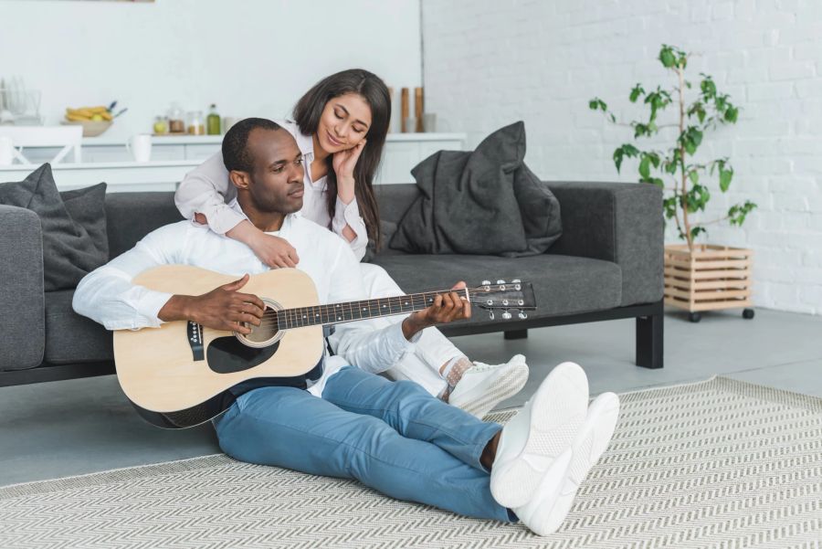 paar im wohnzimmer, mann spielt gitarre