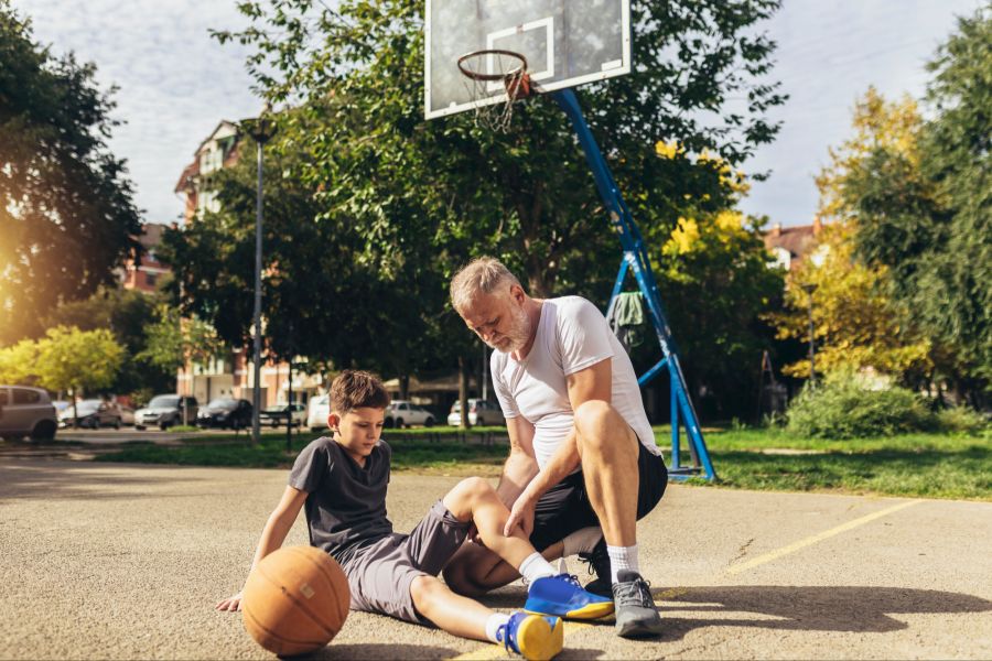 Vater hilft verletztem Jungen auf dem Basketballplatz