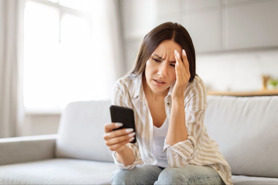 Frau schaut nachdenklich und irritiert auf ihr Smartphone