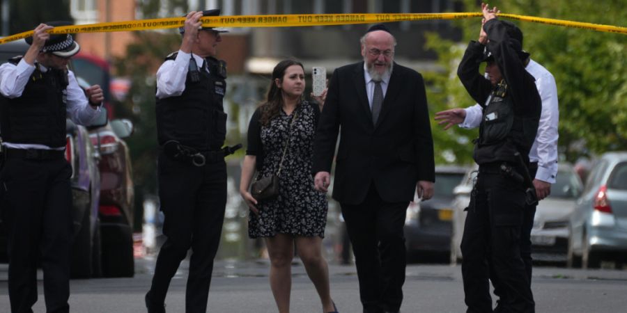 Polizeibeamte öffnen die Absperrung für den Oberrabbiner Ephraim Mirvis, nachdem zwei Menschen im Stadtteil Golders Green bei einem Messerangriff verletzt wurden. Foto: Kin Cheung/AP/dpa