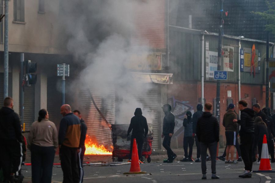 Randalierer stehen vor brennenden Gegenständen in den Strassen von Belfast. Die Unruhen folgten auf antiislamische Proteste in der ganzen Stadt.