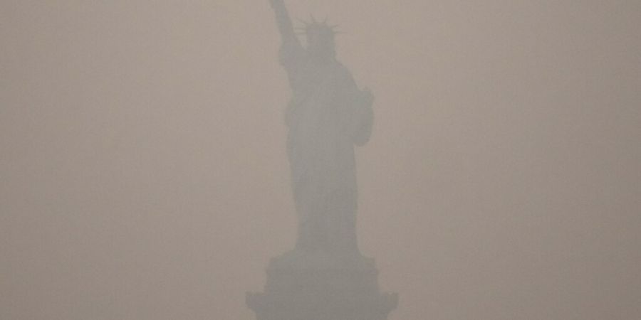 Die Freiheitsstatue ragt bei Sonnenuntergang empor, während Rauch von Waldbränden in Kanada den Himmel verdunkelt. Foto: Yuki Iwamura/AP