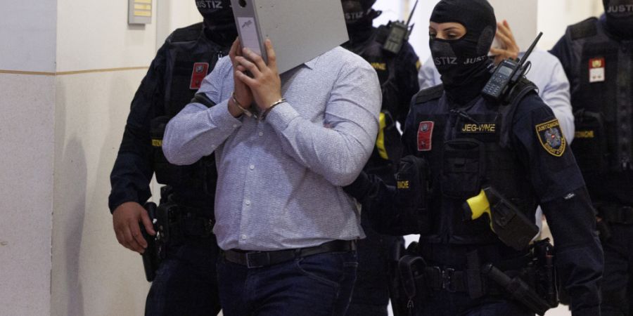 Der Angeklagte im Prozess um mutmaßliche Anschlagspläne auf das Wiener Taylor-Swift-Konzert wird von der Polizei im Gericht begleitet. Foto: Tobias Steinmaurer/APA/dpa